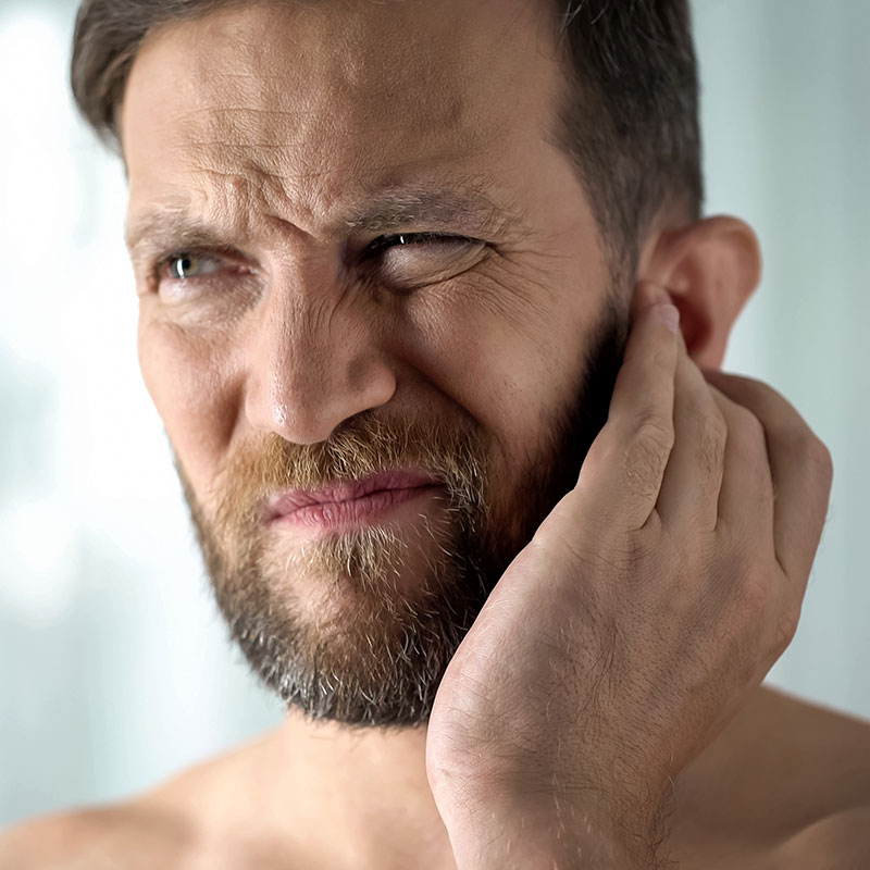 Man holding his ear and wondering which hearing aid style is best for him