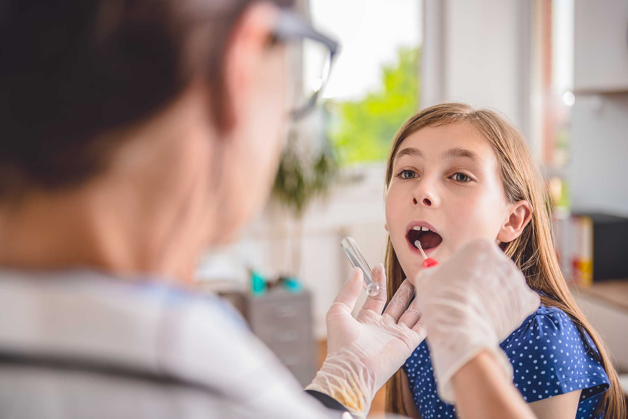 Doctor examining a young girl's tonsils
