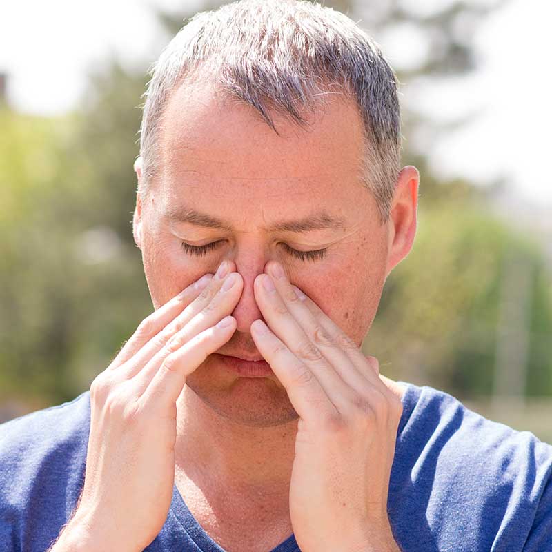 Man holding his nose and wondering if allergy shots will help him
