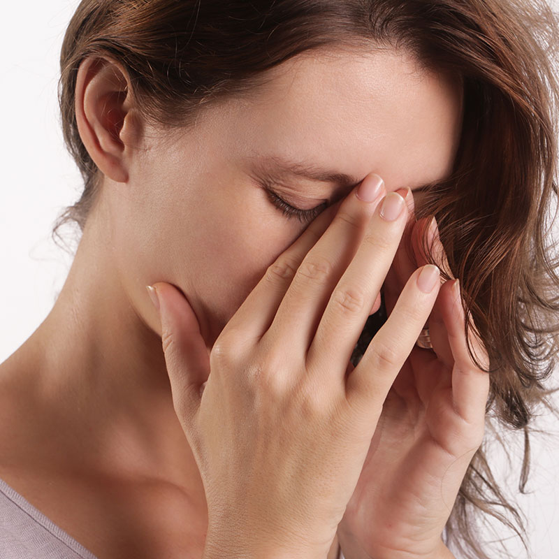 Woman holding the bridge of her nose because she is experiencing sinus pain. 