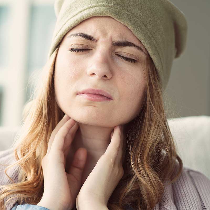 Woman holding her throat and wondering if she has thyroid nodules.