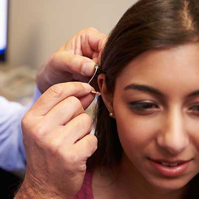 Doctor fitting a woman with her hearing aid