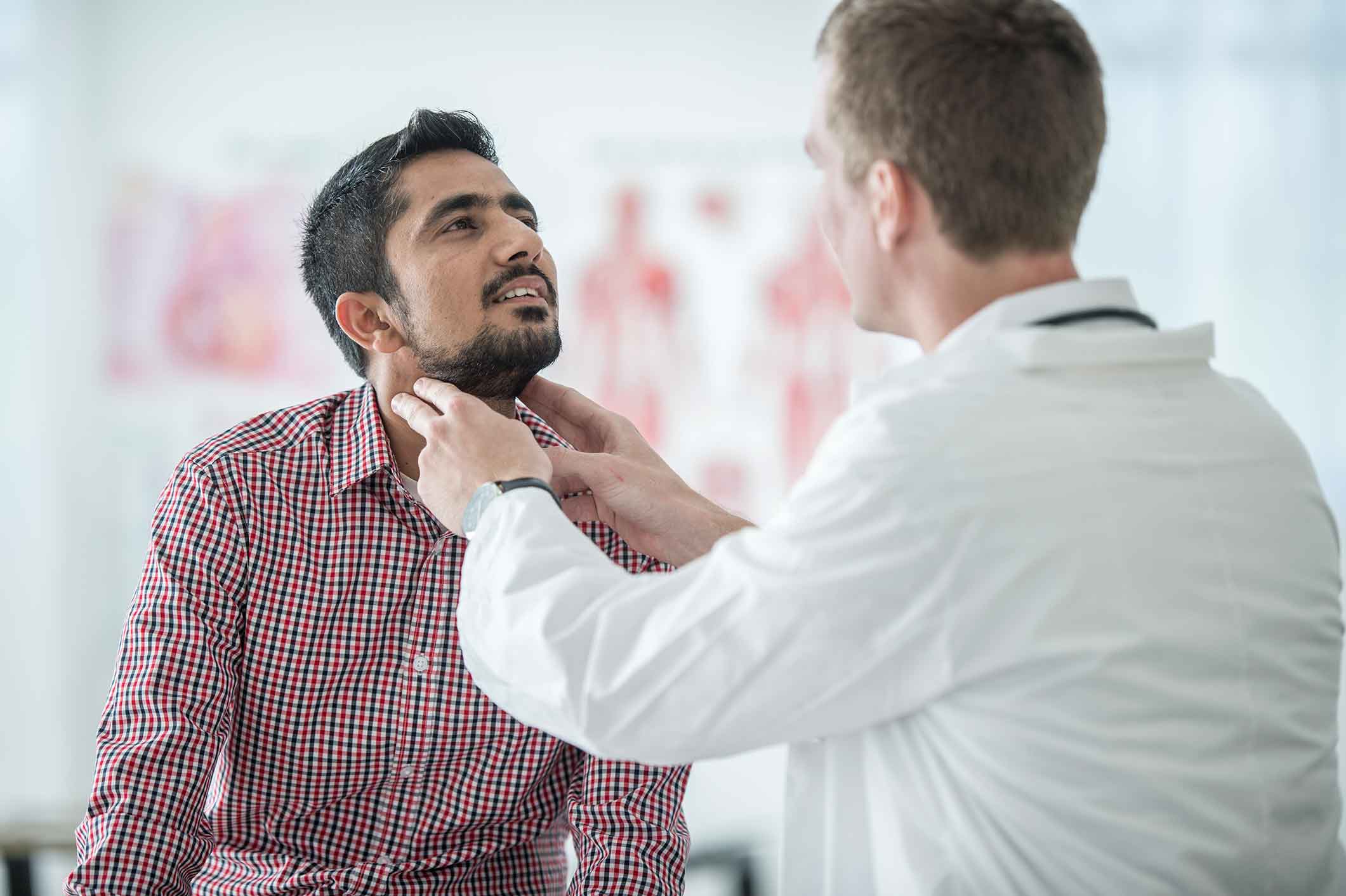 Doctor examining a man's thyroid